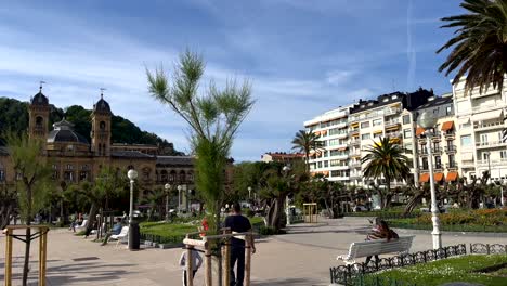 Panorama-shot-of-park-with-people-near-Beach-in-San-Sebastian-during-sunny-day---San-Sebastián-City-Hall-in-background