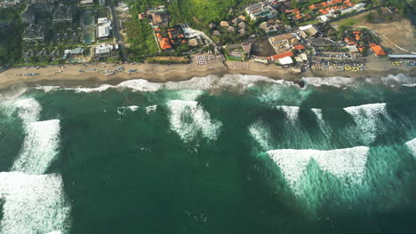 Aerial-birds-eye-shot-of-waves-of-ocean-reaching-Batu-Bolong-Beach-with-surfer-spot-on-Bali---Air-Pollution-and-climate-change-on-island