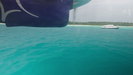 Seaplane-landing-on-blue-tropical-water-in-Maldives-near-island,-window-view