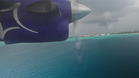 Seaplane-takeoff-from-blue-tropical-water-near-Maldives-island,-window-view-of-engine
