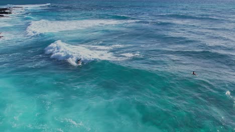 Surfer-riding-turquoise-wave-in-slow-motion---Oahu,-HI-on-a-clear-morning