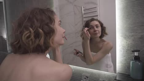 Smiling-woman-using-eyebrow-shadows-make-up-in-front-mirror.-Happy-female-using-beauty-cosmetics-to-improve-herself-ready-to-working-in-bathroom-at-home.-Smilinf-and-blinking-to-a-mirror-reflection