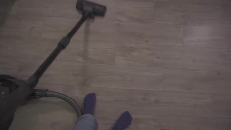 Cropped-footage-of-a-woman's-legs-vacuuming-floor-in-kitchen,-focused-on-cleaning-in-apartment,-holding-pipe.-Housekeeping,-lifestyle-and-creative-people-concept.-Slow-motion.-Top-view