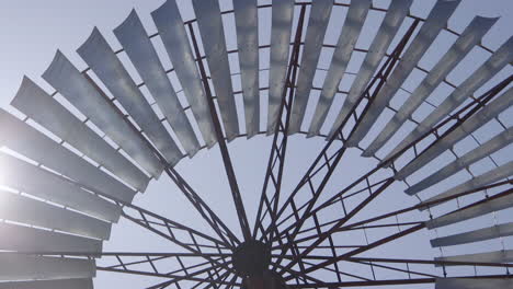 Close-up-largest-old-historic-windmill-and-the-blades-turning-in-the-wind-and-the-suns-rays-between-the-blades