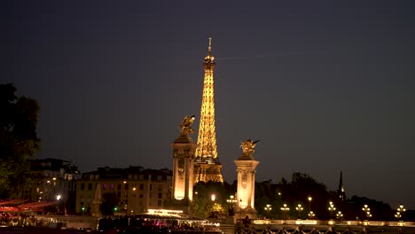 Eiffel-Tower-seen-at-night-behind-the-Bridge-Alexandre-III-in-the-Seine-river-with-night-lights,-View-from-tour-boat