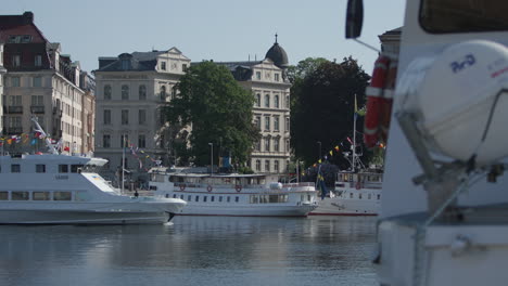 Commuter-ferry-drives-by-quay-and-old-buildings-in-Stockholm,-Sweden