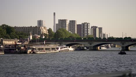 Pont-d'Iéna-near-the-Eiffel-tower-crossing-the-River-Seine-with-Cheminée-du-Front-de-Seine-steam-exhaust-near-buildings-far-away,-View-from-boat