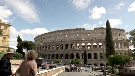 Iconic-Colosseum-Viewed-From-Ponte-degli-Annibaldi-Bridge-On-Sunny-Day-With-Blue-Skies-With-Tourists-In-Background