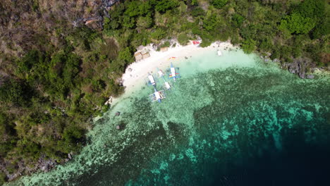 Top-Down-view-cinematic-drone-shot-of-a-tropical-sand-beach-with-boats-on-the-shore-in-Palawan-Philippines,-Aerial