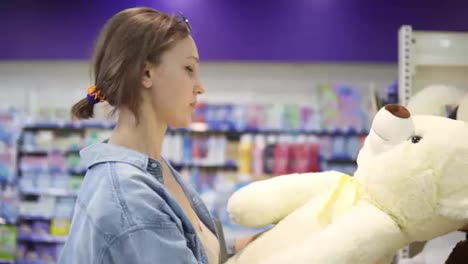Close-up-footage-of-the-girl-looking-for-the-soft-toys-on-the-shelf-in-the-supermarket.-She-is-determined-with-a-choice.-Shelf