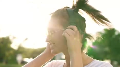 Close-up-of-fair-hair-girl-dancing-to-the-rhythm-of-music-with-headphones.-Front-view-of-a-happy-female-shaking-her-head-in