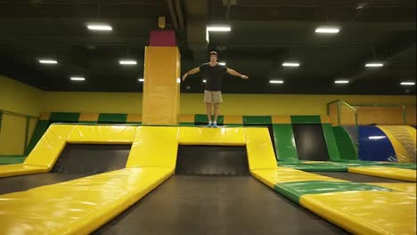 Slowmotion-footage-of-a-young-male-athlete-having-fun-jumping-on-professional-trampoline,-doing-somersaults.