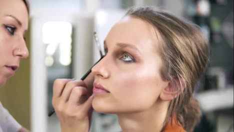 Make-up-studio.-Professional-make-up-artist-doing-make-up-for-a-beautiful-caucasian-model.-Applying-some-eyeshadows-using-a