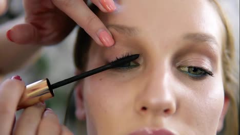 Close-up-of-a-make-up-process,-model's-eyes.-Artist-putting-on-black-mascara.-Front-view