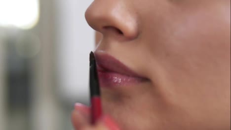 Close-Up-view-of-a-professional-makeup-artist-applying-lipstick-on-model's-lips-working-in-beauty-fashion-industry.-Close-up-view