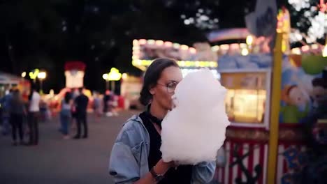 Happy,-young-woman-walking-at-amusement-park-in-summer.-Blonde-female-taking-cotton-candy,-enjoy-her-time,-smiling