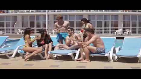 Group-of-beautiful-young-friends-drinking-cocktails-and-having-fun-sitting-by-the-swimming-pool.-Shot-in-4k