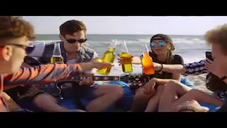 Eine-Gruppe-Von-Freunden-Trinkt-Cocktails-Und-Bier-Und-Jubelt,-Sitzt-Auf-Sesseln-Am-Strand-Und-Hört-Einem-Freund-Zu,-Der-An-Einem-Sommerabend-Gitarre-Spielt.-In-4k-Gedreht.