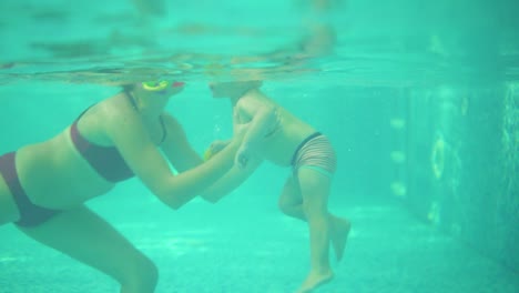 and-underwater-shot-of-cute-blonde-toddler-swimming-under-the-water-together-with-his-mother-in-the-swimming-pool.-Then-his