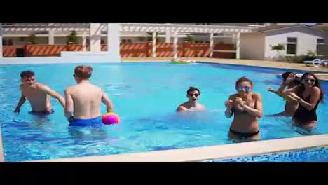 Group-of-young-friends-playing-volley-ball-in-the-swimming-pool.-Summertime-pool-party.-Slowmotion-shot