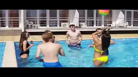 Group-of-young-friends-playing-volley-ball-in-the-swimming-pool.-Summertime-pool-party.-Slowmotion-shot