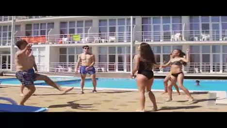Group-of-young-friends-playing-volley-ball-by-the-swimming-pool.-Summertime-pool-party.-Slowmotion-shot