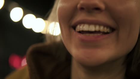 Front-footage-of-young-girl-on-the-night-street-smiling-and-playfully-sticking-out-tongue.-Street-lights-behind