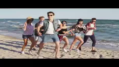 Group-of-young-hipster-friends-running-together-on-a-beach-at-the-water's-edge.-Slowmotion-shot