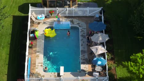 Family-enjoying-pool-party-in-backyard-swimming-pool,aerial-view-USA