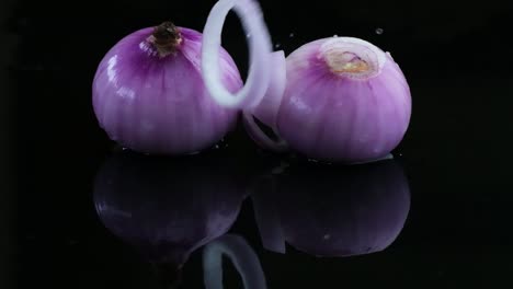 Two-peeled-red-onions-with-an-onion-ring-on-a-wet-surface