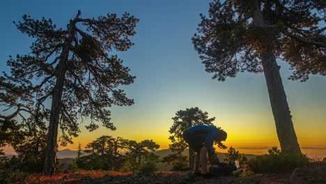 Travelers-setting-hammock-on-tree-trunks-with-magical-sunset-in-background,-time-lapse