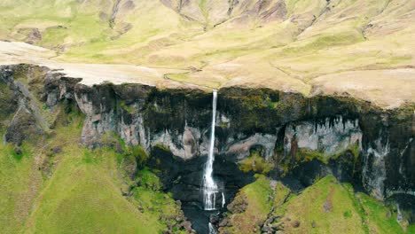 A-long,-thin-waterfall-on-a-high-rocky-escarpment-in-the-mountains,-Iceland
