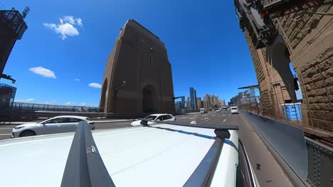 Driving-across-Sydney's-Harbour-Bridge,-the-camera-looks-up,-follows-and-rotates-with-the-arch-of-the-bridge-as-the-vehicle-moves-across-the-deck