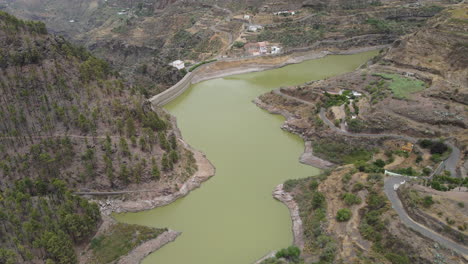 Los-Perez-y-Lugarejos-dam:-aerial-view-traveling-in-to-the-fantastic-dam-with-green-waters-and-the-grove-that-surrounds-it