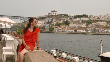 Hermosa-Mujer-Con-Vestido-Rojo-Sentada-En-Porto-En-Douro-En-La-Playa,-Portugal