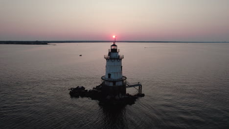 Aerial-ascending-video-revealing-sunset-from-behind-the-Conimicut-Point-Lighthouse-in-Warwick,-RI