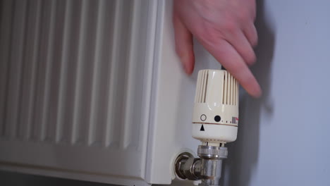 person-turns-down-the-heat-from-the-radiator-to-cool-down-the-house