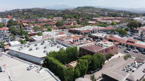 Low-descending-aerial-shot-of-the-Franciscan-Gardens-wedding-venue-with-the-Mission-in-the-background-in-San-Juan-Capistrano,-California