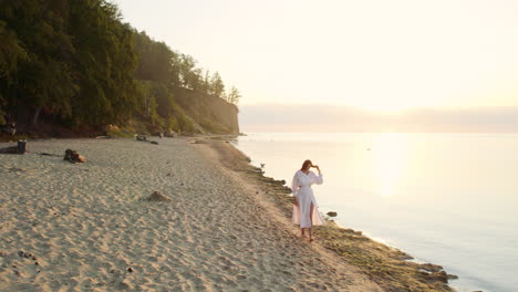 Woman-in-White-Summer-Dress-Strolls-by-the-Sea-at-Sunrise---aerial-parallax-slow-motion