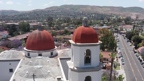 Panning-aerial-close-up-shot-of-the-belltower-and-dome-of-the-Mission-Basilica-in-San-Juan-Capistrano,-California