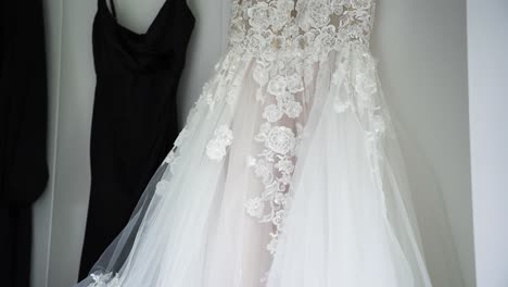 Detail-Of-A-Long-Wedding-Bridal-Gown-Hanging-Beside-Black-Bridesmaid-Dresses