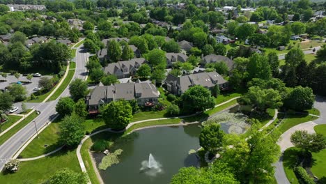 Panoramic-view-of-a-private-gated-community-of-townhomes-and-apartment-complexes-with-beautiful-landscaping,-mature-trees,-walking-paths-and-a-lake-with-a-fountain