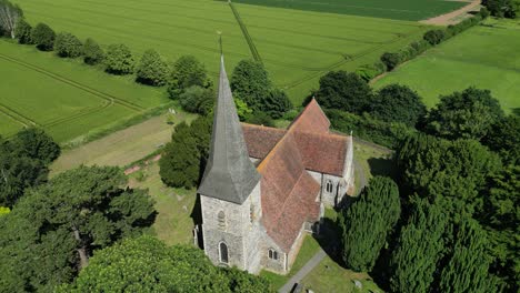 A-slow-aerial-arc-shot-of-St-John-the-Evangelist-church-in-Ickham,-Kent,-during-a-bright-summer-day