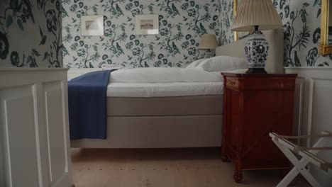 4k-slow-motion-gimbal-push-in-on-traditional-and-luxurious-bedroom-in-a-danish-castle-with-upper-class-furniture,-bed-and-decorations-and-tapestry-on-the-walls