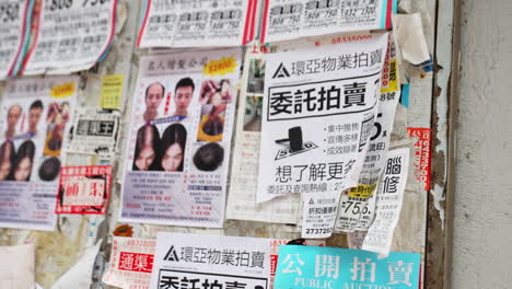Static-shot-of-advertisement-flyers-hanging-on-a-wall-written-in-chinese-ideograms
