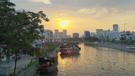 Halten-Sie-Während-Des-Blumenfestes-Die-Atemberaubende-Schönheit-Eines-Sonnenuntergangs-über-Dem-Hafen-Von-Binh-Dong-Fest,-Mit-Schiffen,-Dem-Fluss-Und-Der-Stadtlandschaft-Als-Atemberaubender-Kulisse