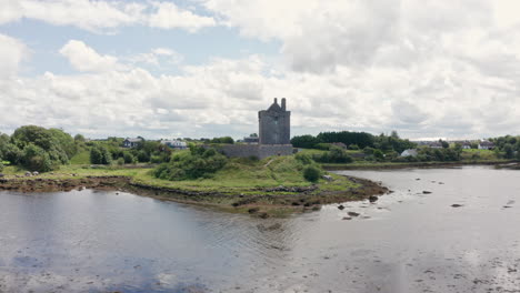 Aerial-Reverse-Shot-Over-Water-of-Dunguaire-Castle-in-County-Galway,-Ireland