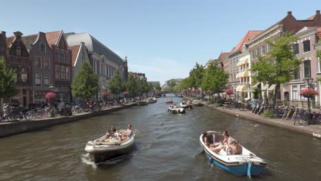 People-Sailing-With-Motor-Boats-Along-The-Canal-During-Summer-In-Leiden,-South-Holland,-Netherlands