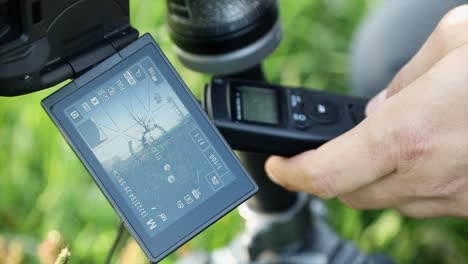 The-photographer-touches-the-camera-display-and-holds-the-intervalometer-in-the-other-hand-for-time-lapse-photography