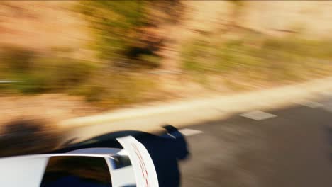 FPV-aerial-following-a-Porsche-911-GT3-driving-through-the-hills-of-Catalonia,-Spain